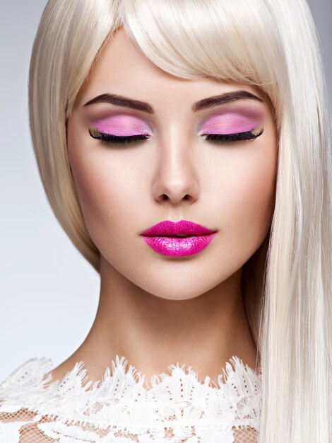 Портрет красивой женщины с розовым макияжем и белыми прямыми волосами. Лицо фотомодели с розовой помадой.
