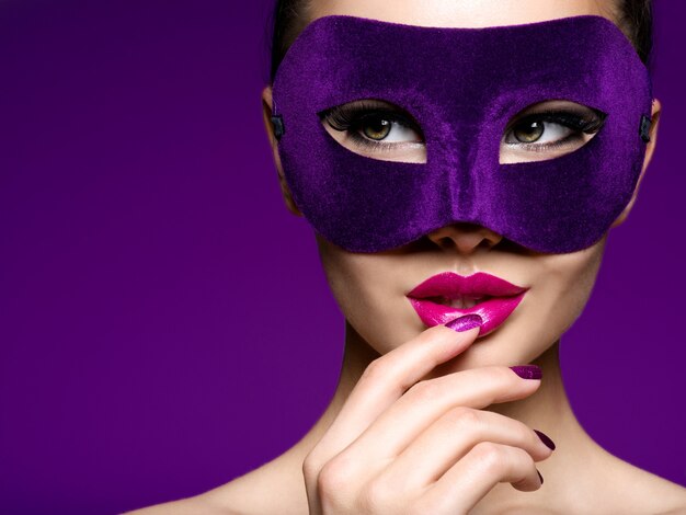 Portrait of a beautiful  woman with purple nails and violet theatre mask on face.