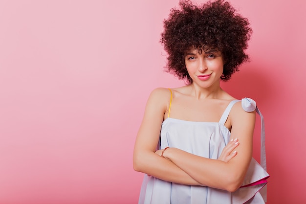 Free photo portrait of beautiful woman with short curly hair and big blue eyes poses on pink with lovely smile