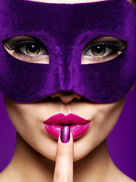 Portrait of a beautiful  woman with violet nails and theatre mask on face.