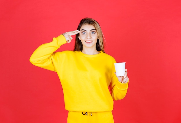 Portrait of beautiful woman in yellow outfit posing with cup of tea
