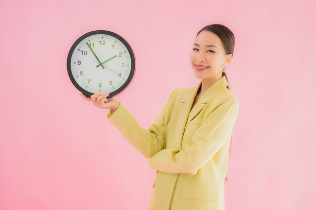 肖像 美丽的年轻亚洲女商人 显示时钟或报警在颜色隔离