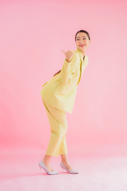 Ritratto bello giovane sorriso asiatico della donna di affari nell'azione sul colore rosa