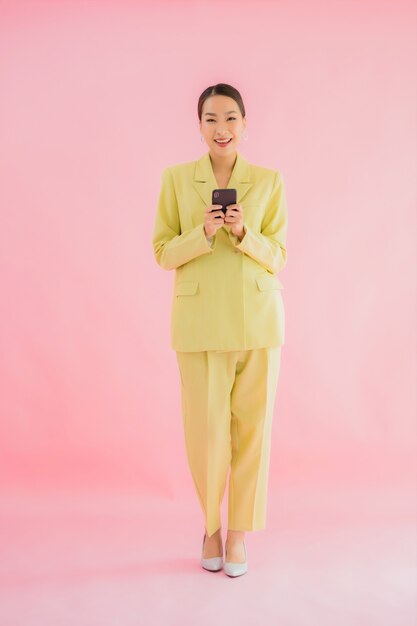 Portrait beautiful young asian business woman use smart mobile phone with coffee cup on color