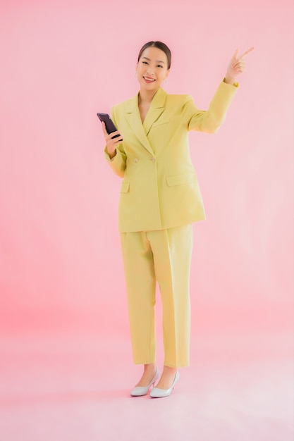 세로 아름 다운 젊은 아시아 비즈니스 여자 색상에 커피 컵과 스마트 휴대 전화를 사용