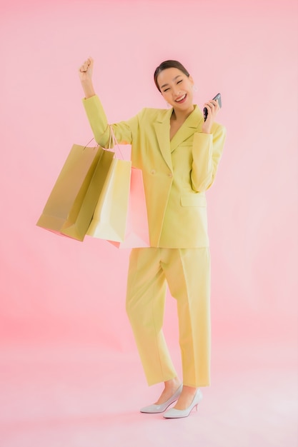 分離された色の買い物袋を持つ美しい若いアジアビジネス女性の肖像画