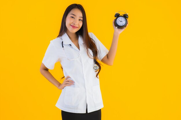 아름 다운 젊은 아시아 의사 여자의 초상화 알람 시계를 보여줍니다