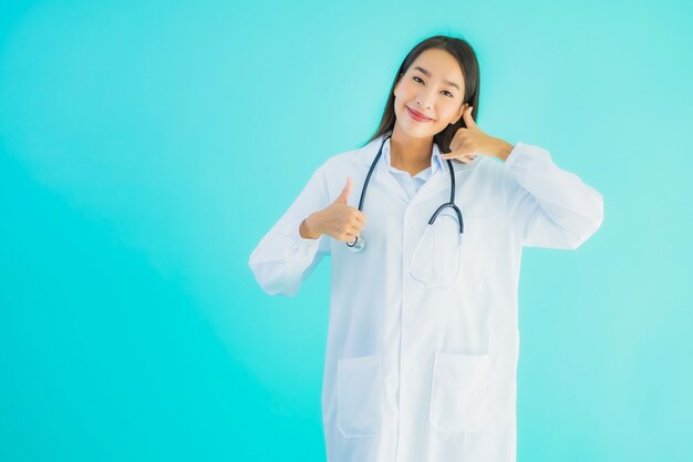 肖像画の美しい若いアジア医師の女性はモバイルスマート携帯電話を使用します。
