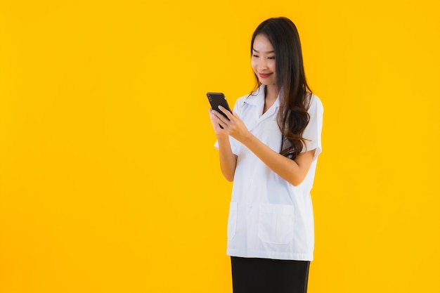 美しい若いアジア医師の女性の肖像画は、スマートフォンを使用しています