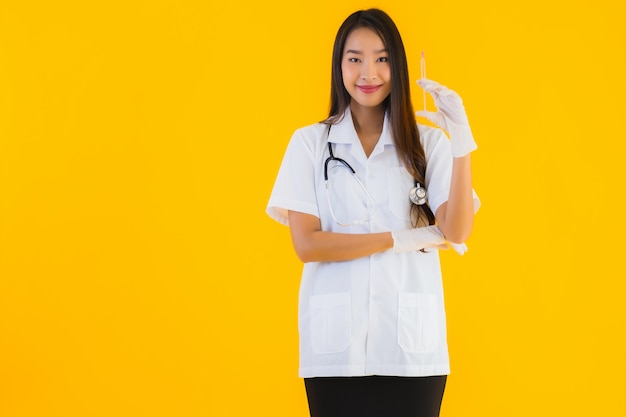 美しい若いアジア医師の女性の肖像画は手袋を着用し、注射器を使用
