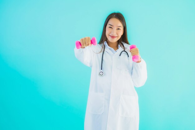 肖像画ダンベルを持つ美しい若いアジア医師女性