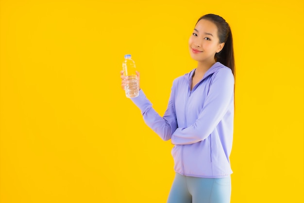 Женщина спорта портрета красивая молодая азиатская готовая для тренировки на желтом цвете