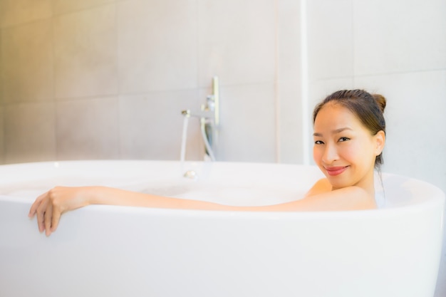 욕조에 초상화 아름 다운 젊은 아시아 여자 목욕을