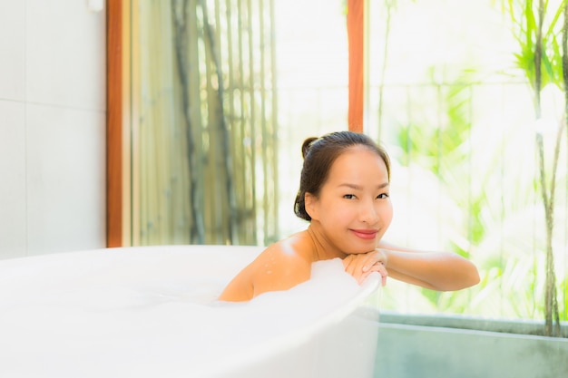 욕조에 초상화 아름 다운 젊은 아시아 여자 목욕을