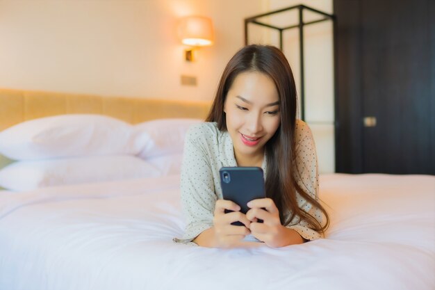 Portrait beautiful young asian woman on bed with smart mobile phone