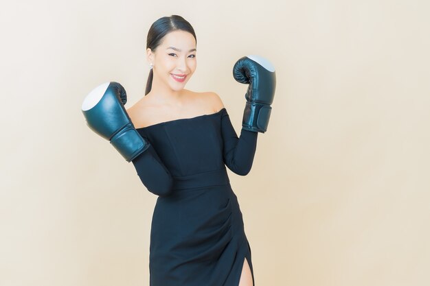 Portrait beautiful young asian woman boxing with glove on yellow