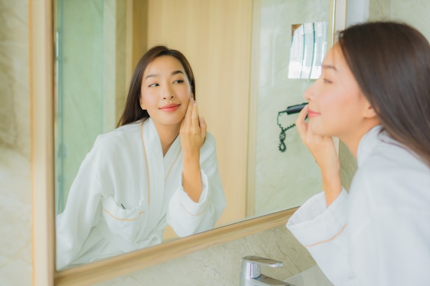 Portrait beautiful young asian woman check up face in bathroom