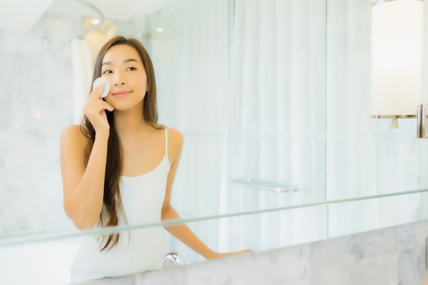 Портрет красивая молодая азиатская женщина проверяет и составляет ее лицо