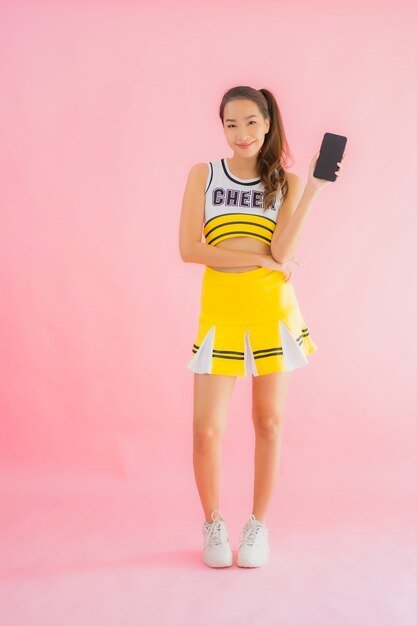 肖像画のスマートな携帯電話を持つ美しい若いアジア女性チアリーダー