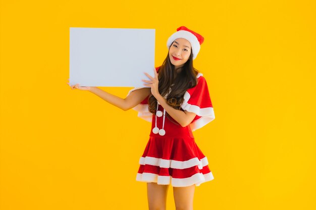 세로 아름 다운 젊은 아시아 여자 크리스마스 옷과 모자 빈 보드와 미소