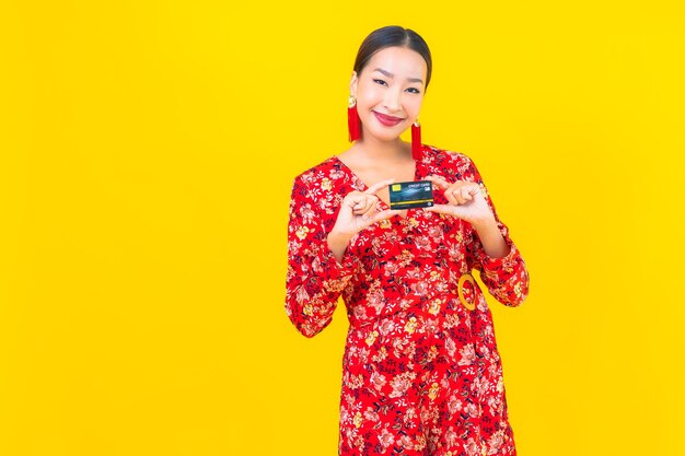 Portrait beautiful young asian woman credit card for shopping on yellow isolated wall