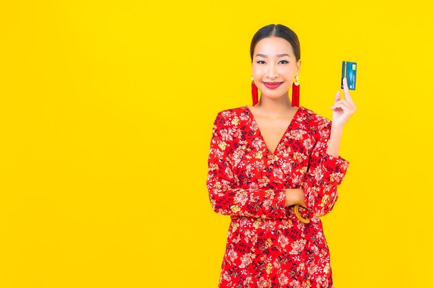 Portrait beautiful young asian woman credit card for shopping on yellow isolated wall
