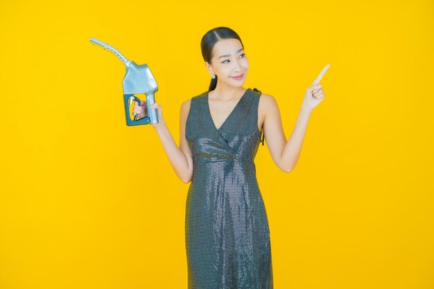 Portrait beautiful young asian woman feul gas pump on yellow