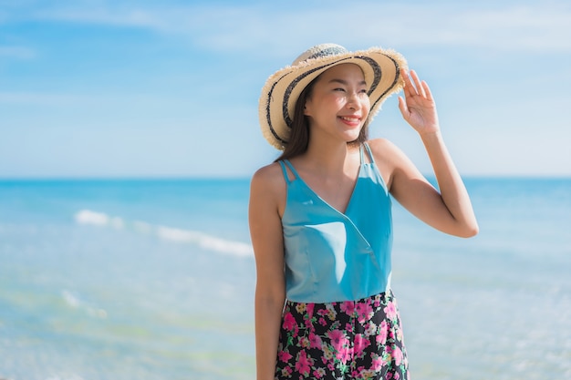 Il sorriso felice della bella giovane donna asiatica del ritratto si rilassa intorno all'oceano ed al mare della spiaggia