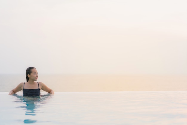 Il sorriso felice della bella giovane donna asiatica del ritratto si rilassa intorno alla piscina nella località di soggiorno dell'hotel