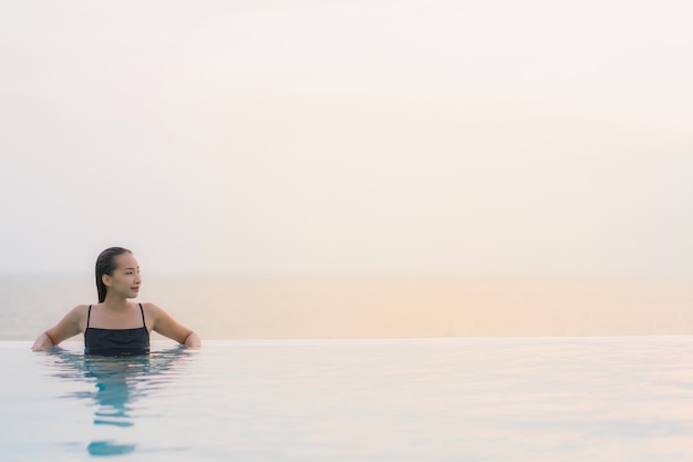 초상화 아름 다운 젊은 아시아 여자 행복 한 미소와 호텔 리조트 수영장 주위에 휴식