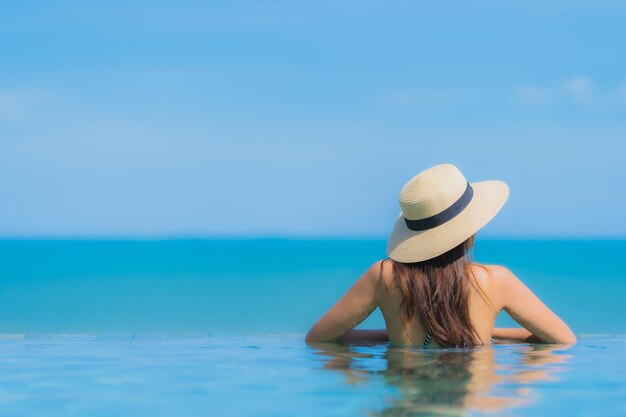 Портрет красивой молодой азиатской женщины счастливой улыбкой расслабиться в бассейне на курорте отеля Neary Sea Ocean Beach на голубом небе
