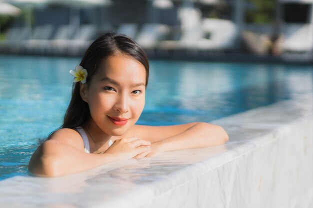リゾートやホテル周辺のスイミングプールでの肖像画美しい若いアジア女性幸せな笑顔