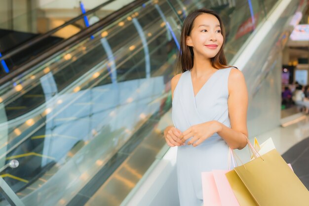 Женщина портрета красивая молодая азиатская счастливая и улыбка с хозяйственной сумкой от универмага
