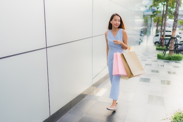 幸せな肖像画美しい若いアジア女性とデパートからの買い物袋と笑顔