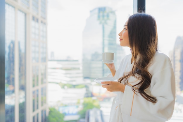 Free photo portrait beautiful young asian woman hold coffee cup with city view