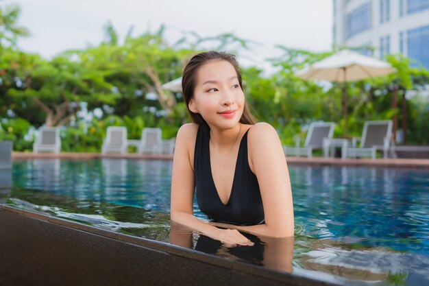 肖像画の美しい若いアジア女性レジャーリラックス休暇の屋外スイミングプールの周りの笑顔