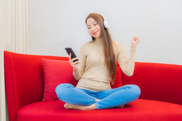 Portrait of beautiful young asian woman listens to music on sofa in living room interior