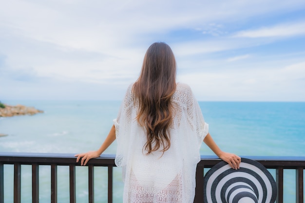 La bella giovane donna asiatica del ritratto che guarda l'oceano della spiaggia del mare per si rilassa nel viaggio di vacanza di festa