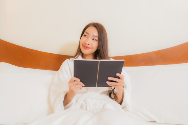 침실 인테리어에 침대에서 책을 읽고 초상화 아름 다운 젊은 아시아 여자