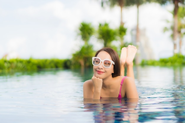 肖像画の美しい若いアジア女性リラックス休暇休暇で屋外スイミングプールの周りをお楽しみください。