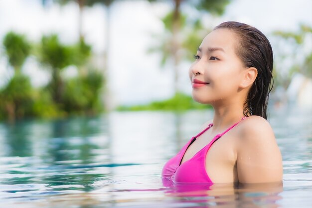 Женщина портрета красивая молодая азиатская ослабляет наслаждается вокруг открытого бассейна в отпуске