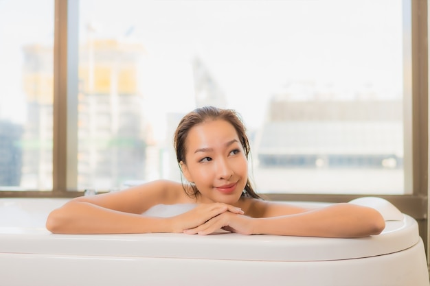 초상화 아름 다운 젊은 아시아 여자 휴식을 즐길 욕실 인테리어에 욕조에서 목욕을 즐길 수