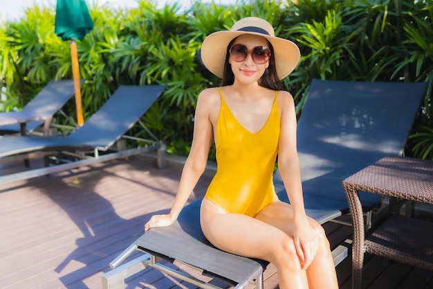 Женщина портрета красивая молодая азиатская ослабляет счастливую улыбку вокруг открытого бассейна в курорте гостиницы на отдыхе