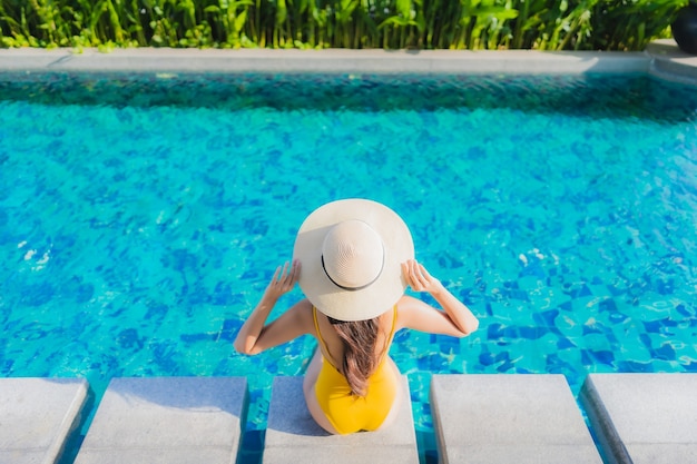 세로 아름 다운 젊은 아시아 여자 레저 휴가를위한 호텔 리조트의 야외 수영장 주변에 행복한 미소를 휴식