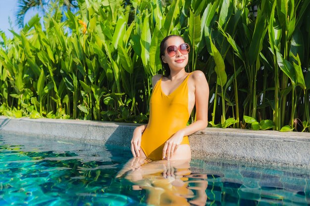 세로 아름 다운 젊은 아시아 여자 레저 휴가를위한 호텔 리조트의 야외 수영장 주변에 행복한 미소를 휴식