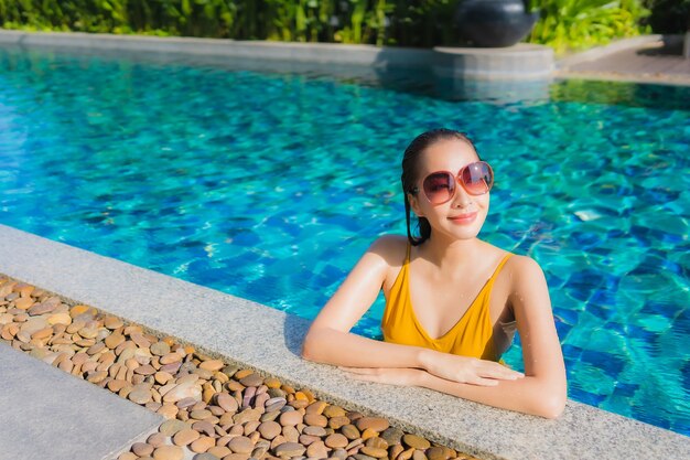 Portrait beautiful young asian woman relax happy smile around outdoor swimming pool in hotel resort for leisure vacation