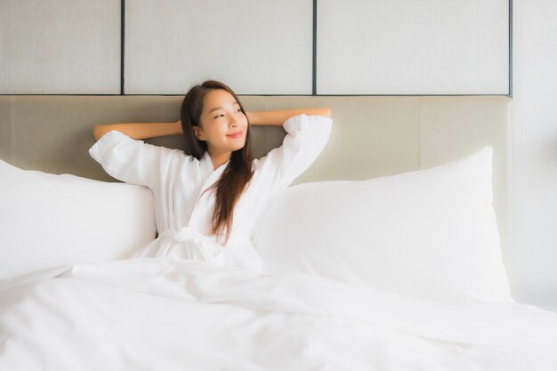 肖像画の美しい若いアジア女性は寝室で幸せな笑顔をリラックスします。
