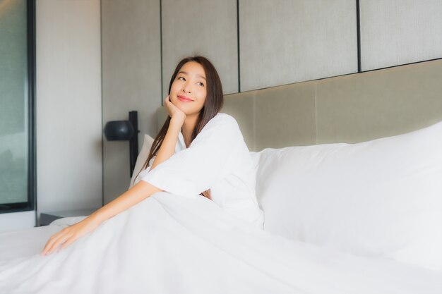Женщина портрета красивая молодая азиатская ослабляет счастливую улыбку в спальне