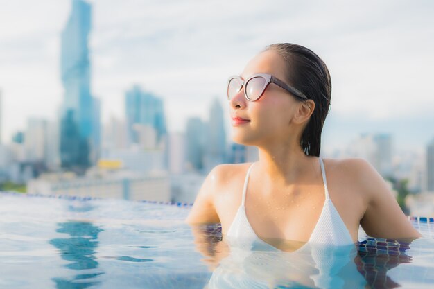 무료 사진 초상화 아름 다운 젊은 아시아 여자는 야외 수영장 주위에 행복한 미소 레저 휴식