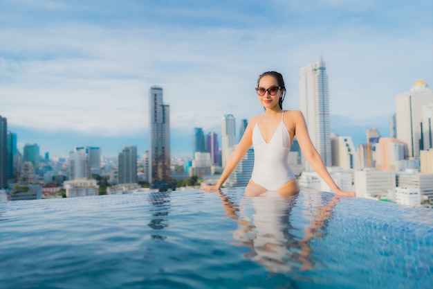 Foto gratuita la bella giovane donna asiatica del ritratto si rilassa lo svago felice di sorriso intorno alla piscina all'aperto